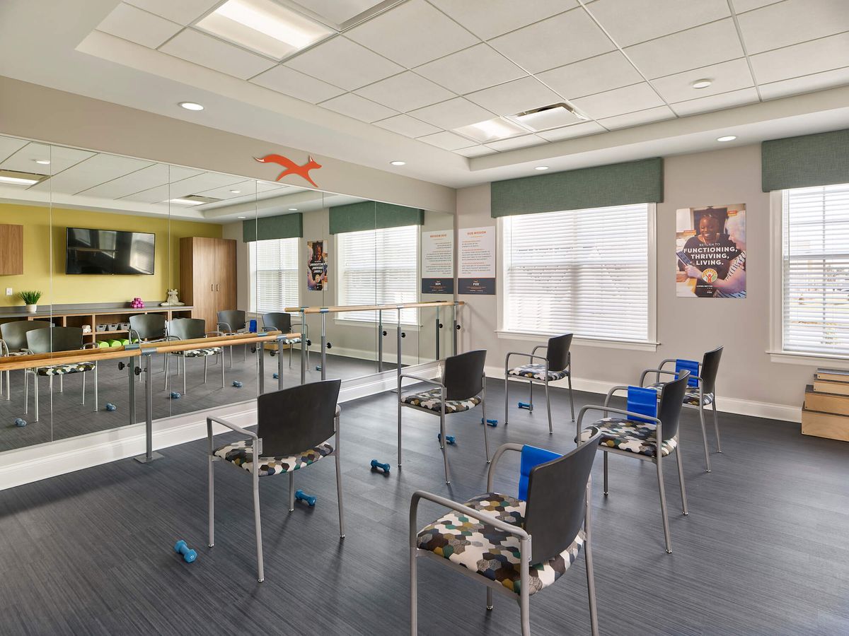 A well-equipped physical therapy room with chairs and exercise equipment.