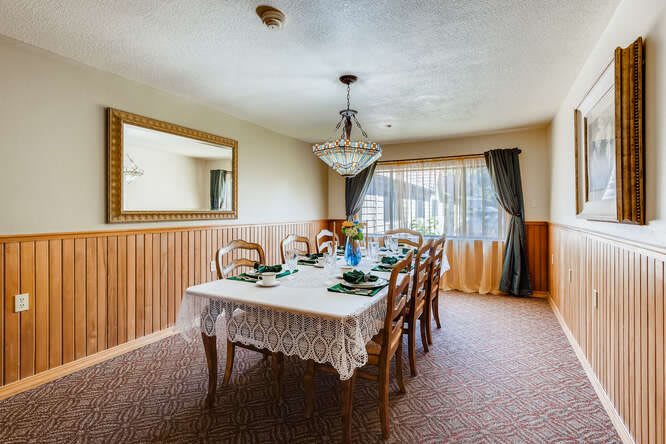 A cozy dining room with a chandelier and a large table set for dinner.