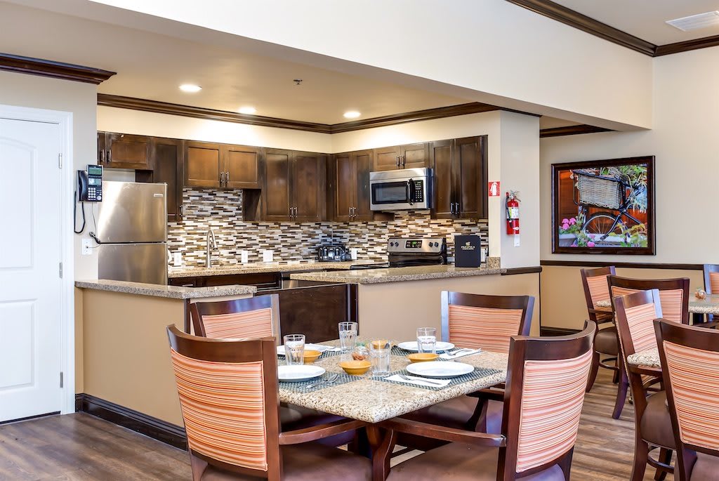 A modern kitchen and dining area with wooden cabinets, stainless steel appliances, and a dining table set for four.