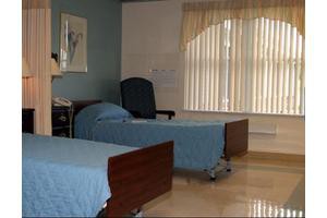 A hospital room with two beds and a window with blinds.