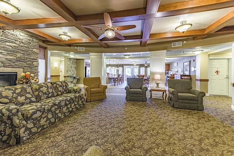 A spacious living room with comfortable seating, warm lighting, and a ceiling fan.