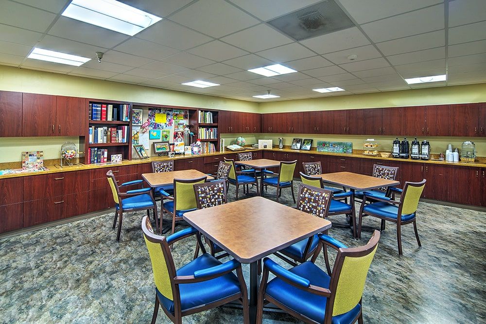 A library seating area with tables and chairs surrounded by bookshelves.