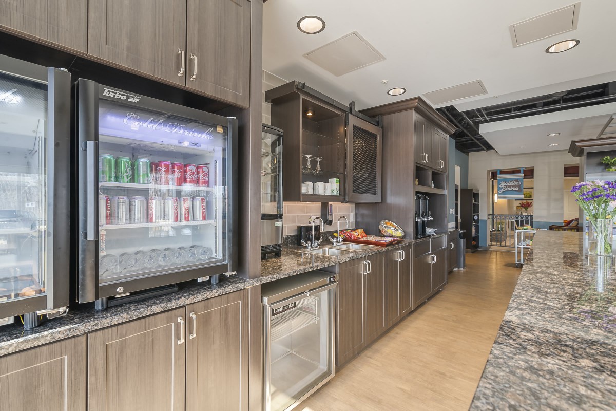 A modern kitchen interior featuring sleek cabinets and a glass-front refrigerator.