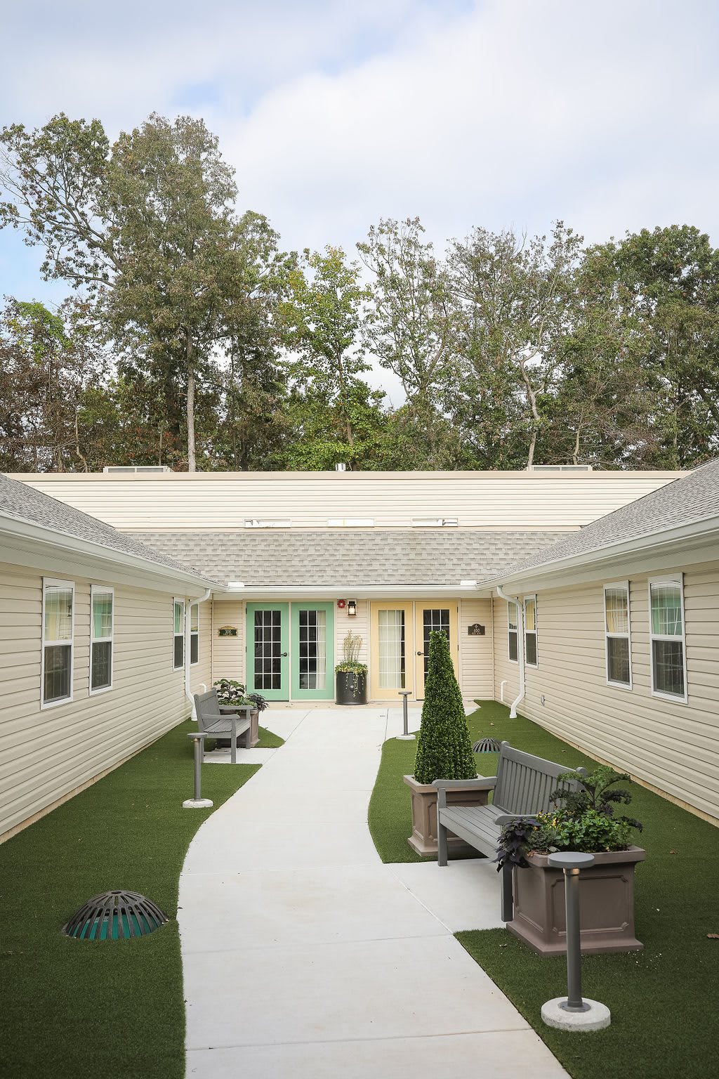 A peaceful courtyard with benches, greenery, and an inviting pathway surrounded by buildings.