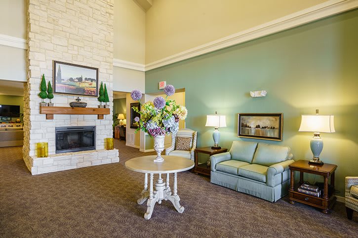 A cozy living room with a fireplace, floral decorations, and comfortable seating.
