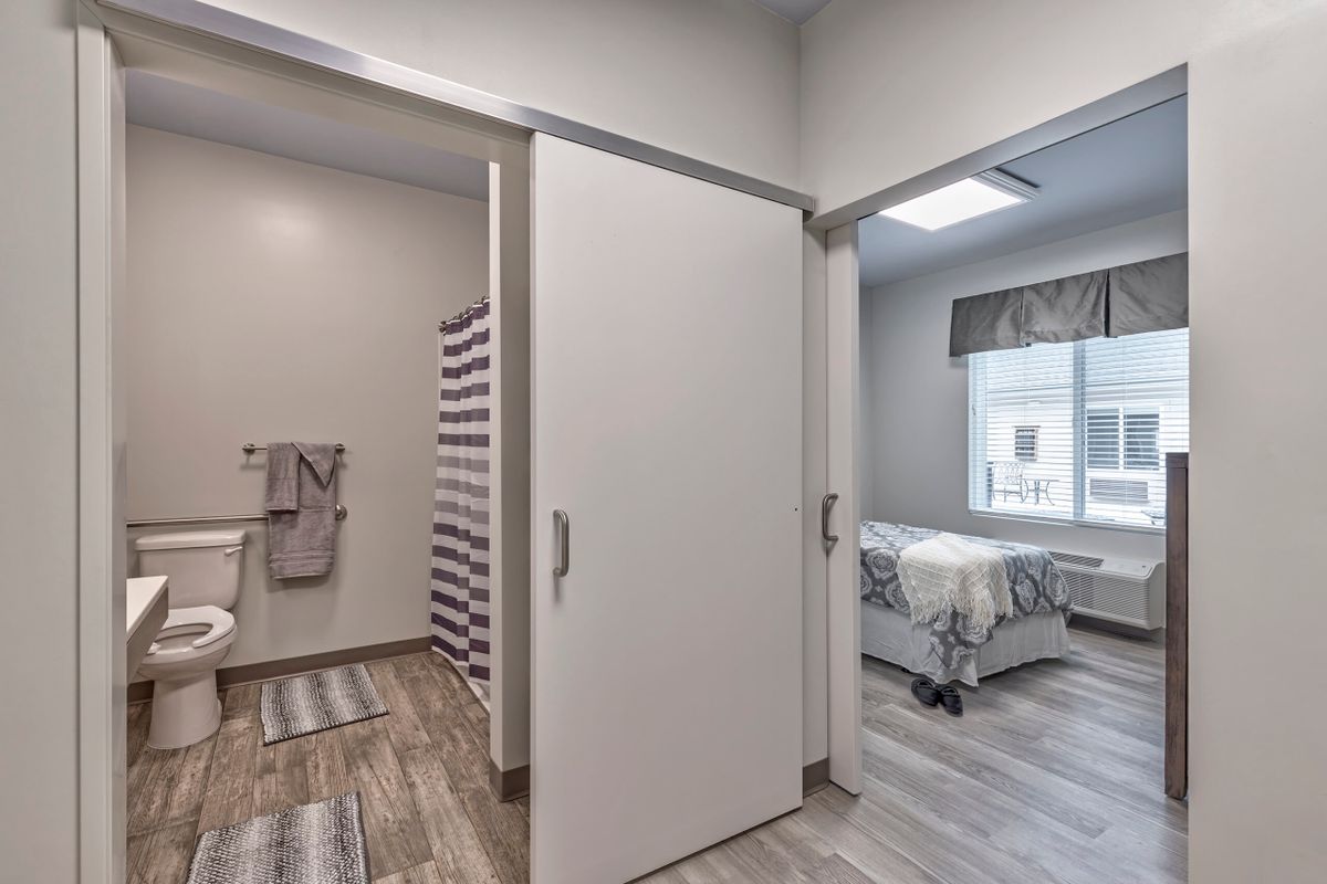 A modern interior view showing a bedroom and bathroom with a sliding door separating the spaces.
