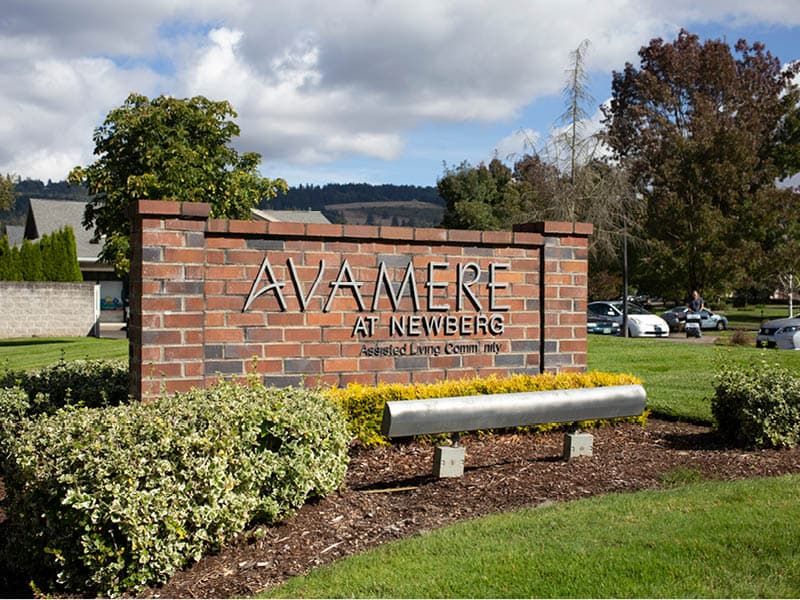 A brick sign for Avamere at Newberg, located in a landscaped outdoor area.