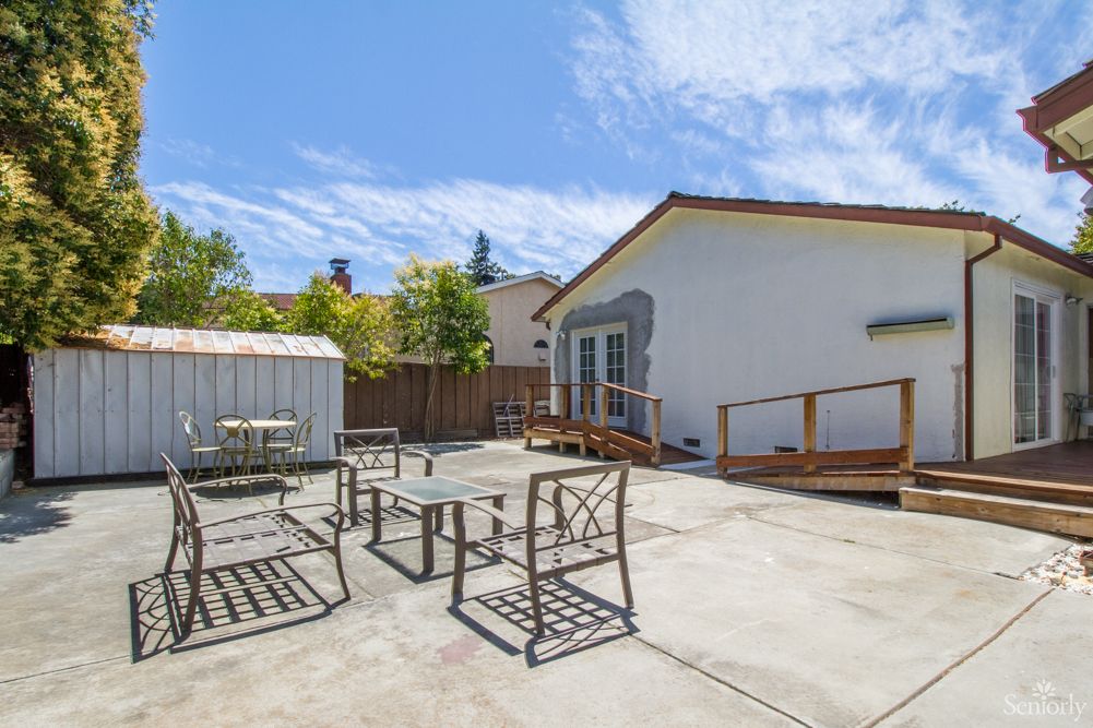 A spacious backyard with outdoor seating, a shed, and a sunny atmosphere.