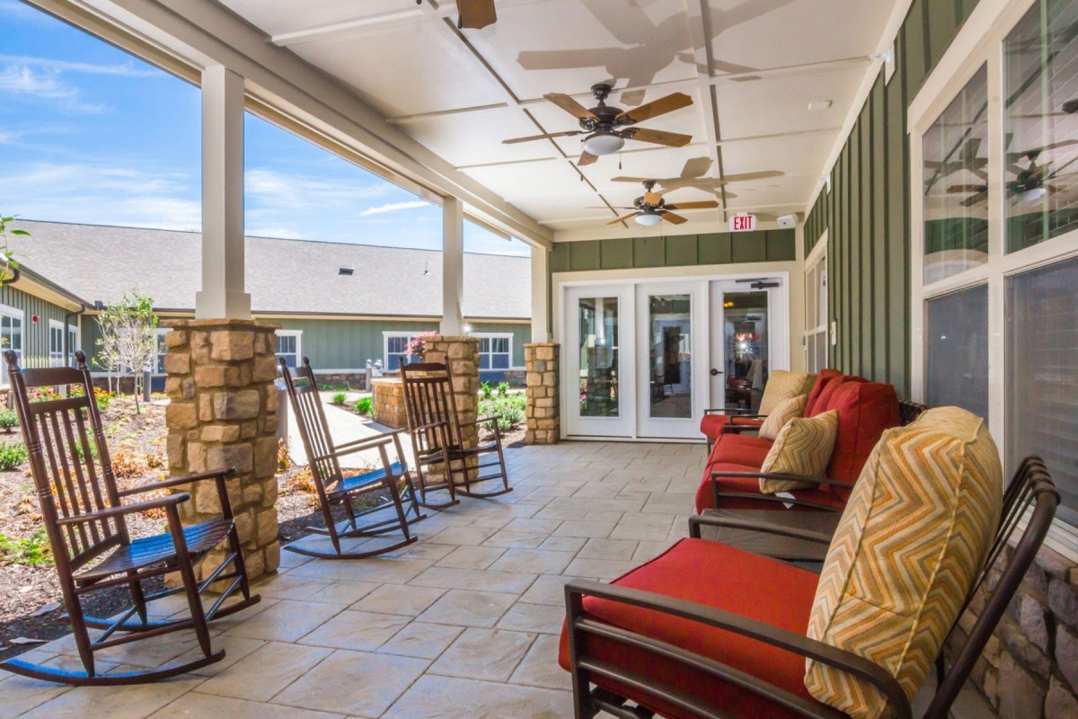 A cozy outdoor patio with rocking chairs and ceiling fans, offering a relaxing seating area.