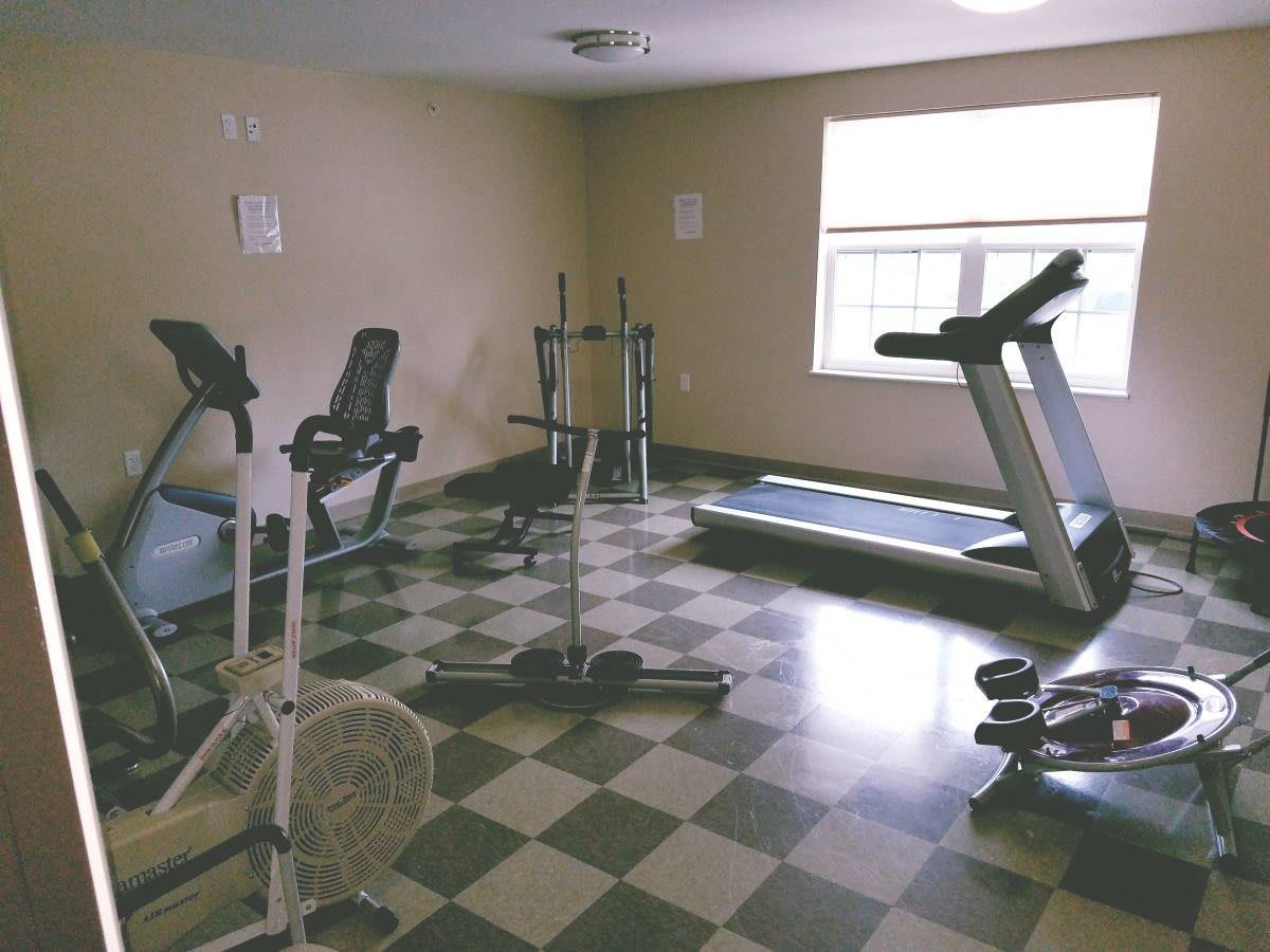 A small gym with various exercise equipment, including a treadmill and stationary bikes.