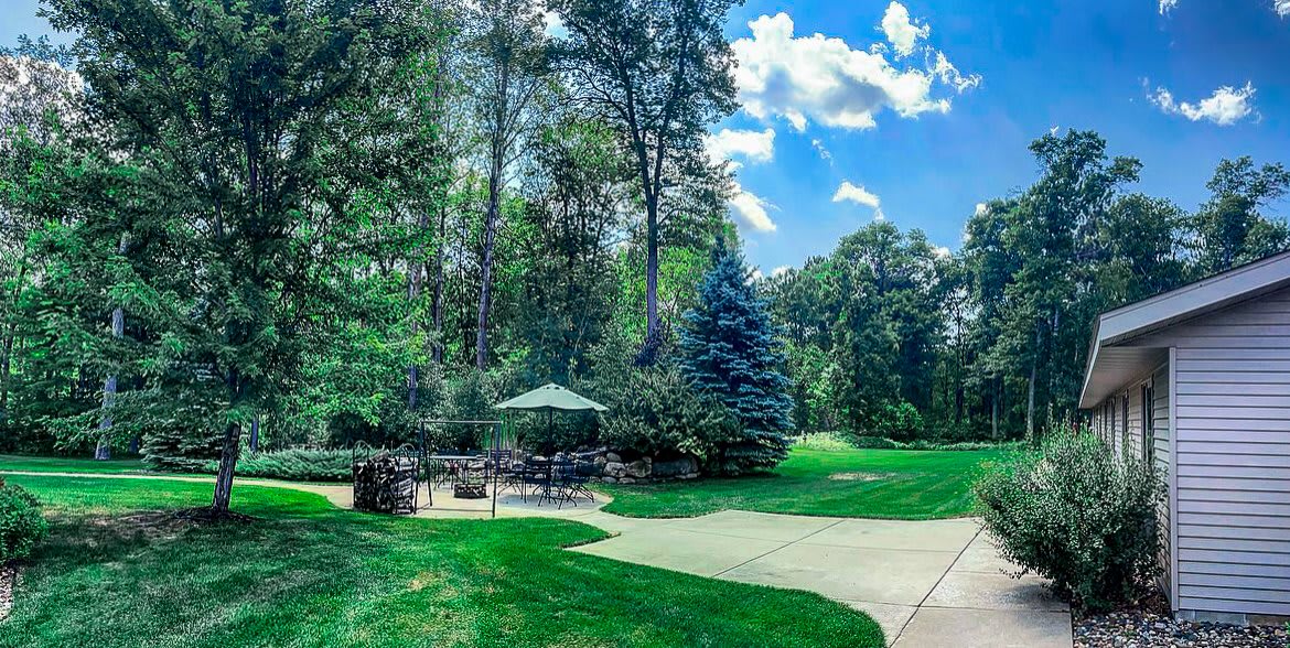 A serene outdoor setting with lush greenery, trees, and a clear blue sky.