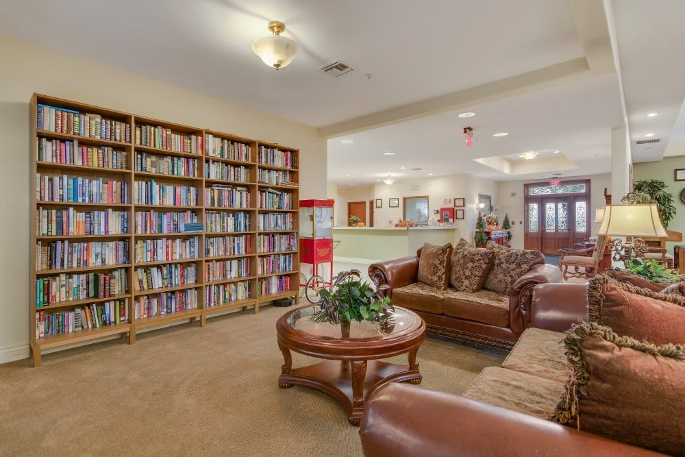 A cozy library and seating area featuring bookshelves, comfortable sofas, and a central table.