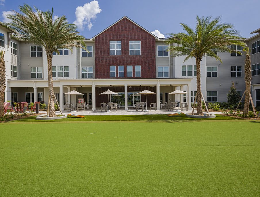 A modern residential building with a well-maintained lawn and palm trees.