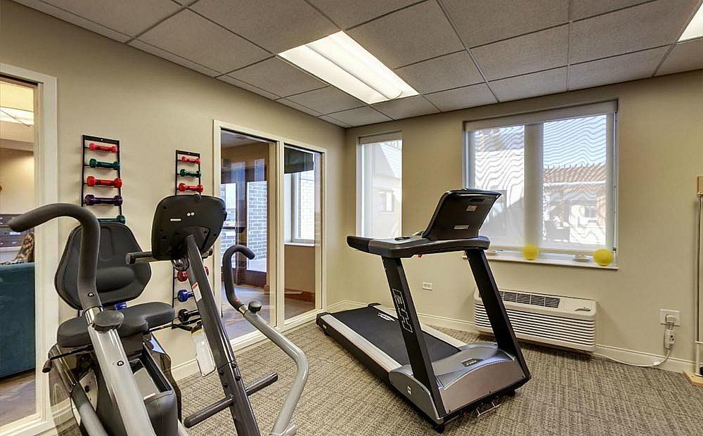 A small fitness room with a treadmill and other cardio equipment.