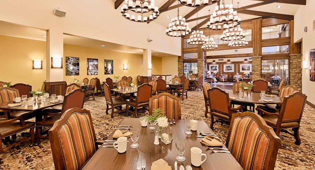 A cozy dining area with elegant chandeliers and neatly arranged tables and chairs.