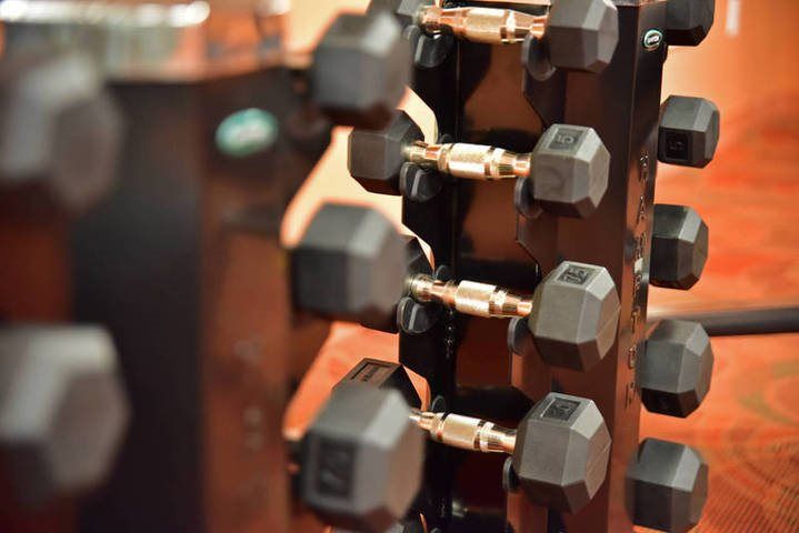 A rack of hex dumbbells in a gym setting.