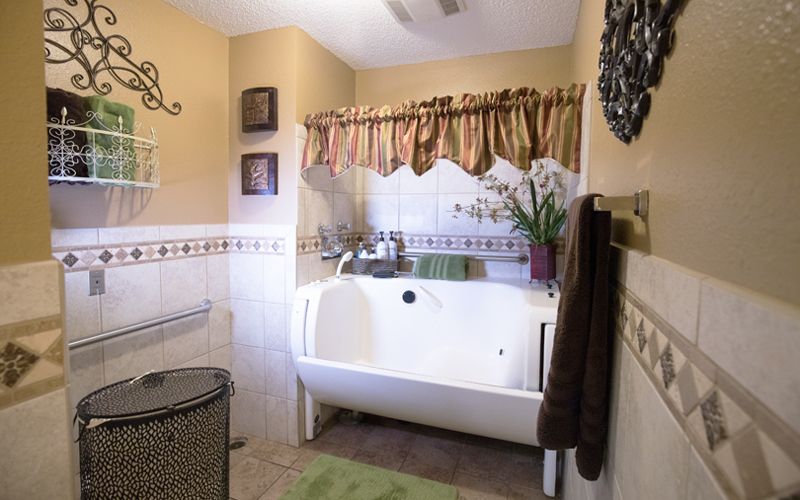 A cozy bathroom featuring a bathtub with decorative elements and plants.