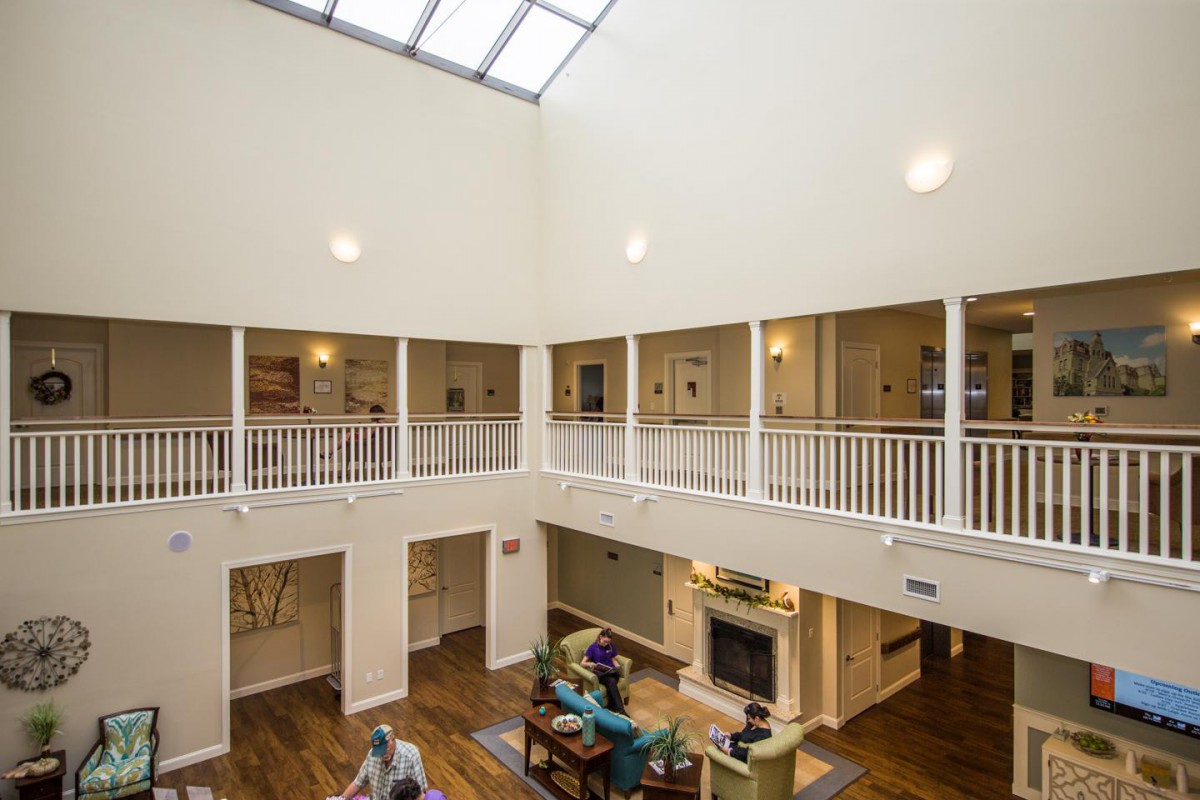 A spacious living room with a high ceiling and skylight, featuring modern furniture and an upper level balcony.