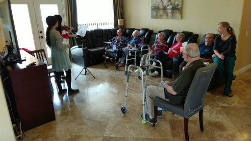 A music performance takes place at a rehabilitation center, where seniors enjoy the entertainment in a cozy indoor environment.