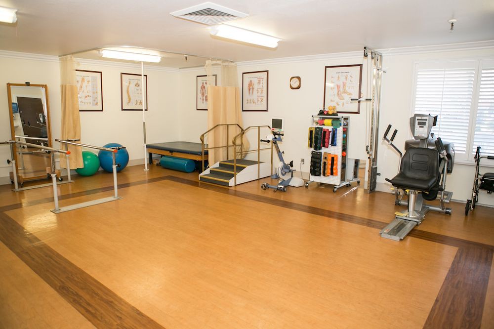A well-equipped gym or therapy room featuring various exercise machines and tools.
