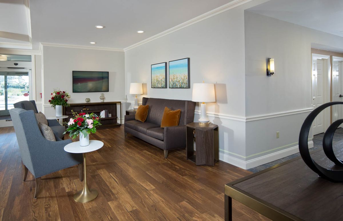 A modern living room with hardwood floors, featuring a brown sofa, decorative pillows, and elegant lighting.
