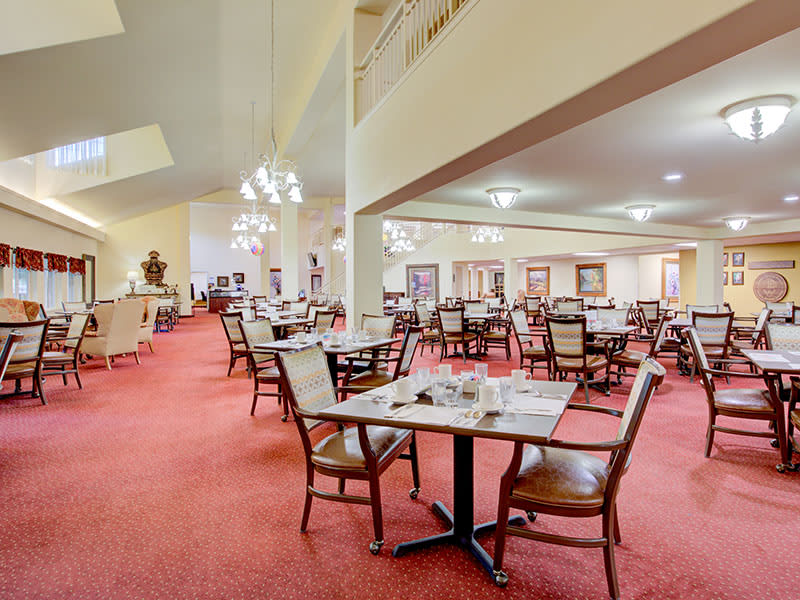 Spacious restaurant dining area with elegant chandeliers and neatly arranged tables.