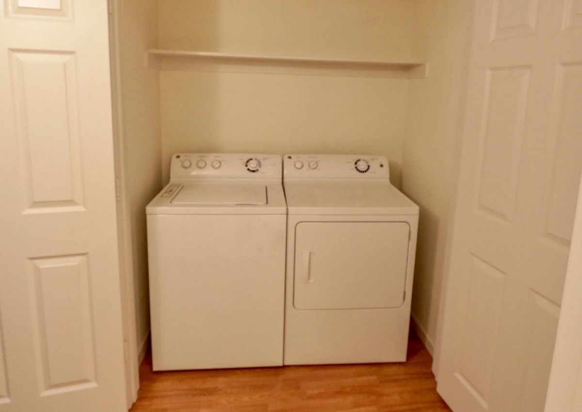 A compact laundry room setup with a washer and dryer beneath a shelf.