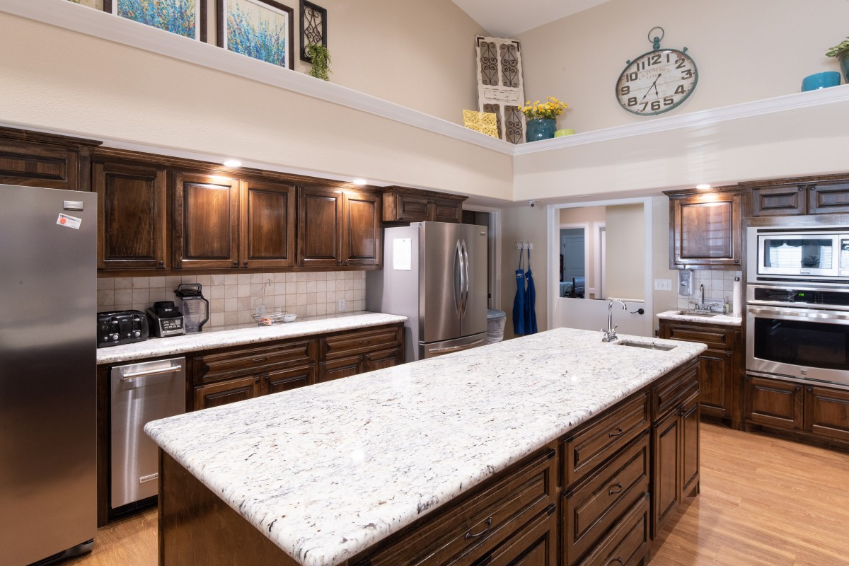 A modern kitchen with a large granite countertop and wooden cabinets.