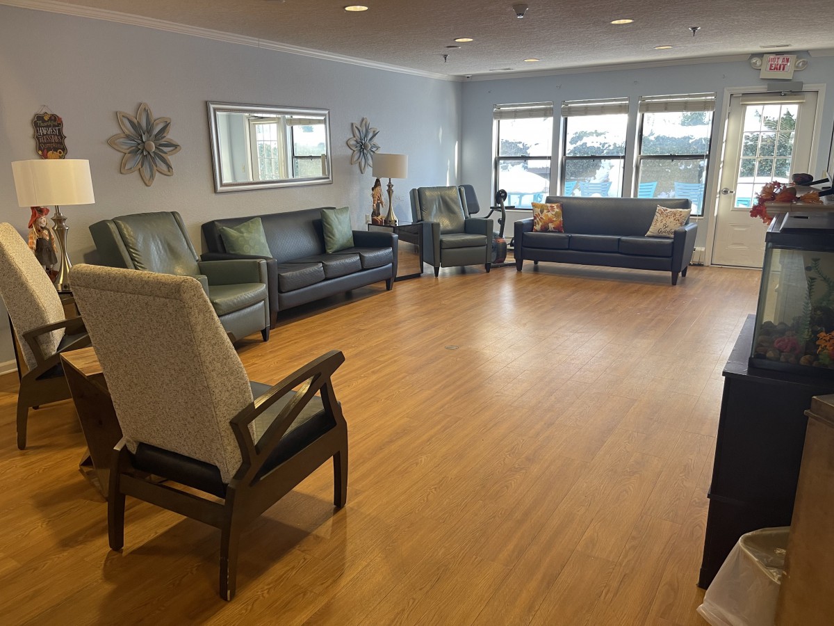 A spacious living room with multiple sofas and chairs arranged on a laminate floor.