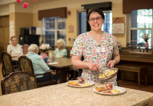A dedicated healthcare worker serves meals in an assisted living facility, ensuring the residents receive nutritious food.