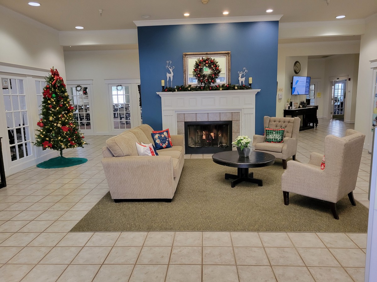 A cozy living room decorated for the holidays with a fireplace and Christmas tree.
