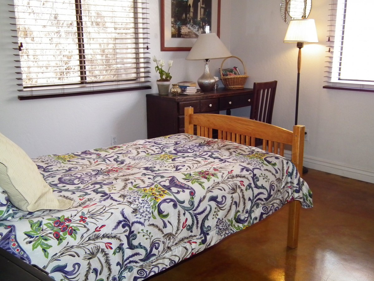 A cozy bedroom with a patterned bedspread and wooden furniture.
