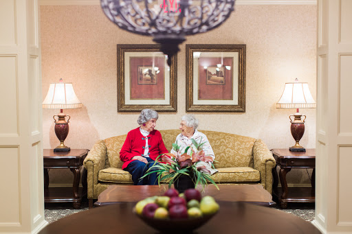Two seniors engaged in a warm conversation while seated on a comfortable couch in a cozy living space.