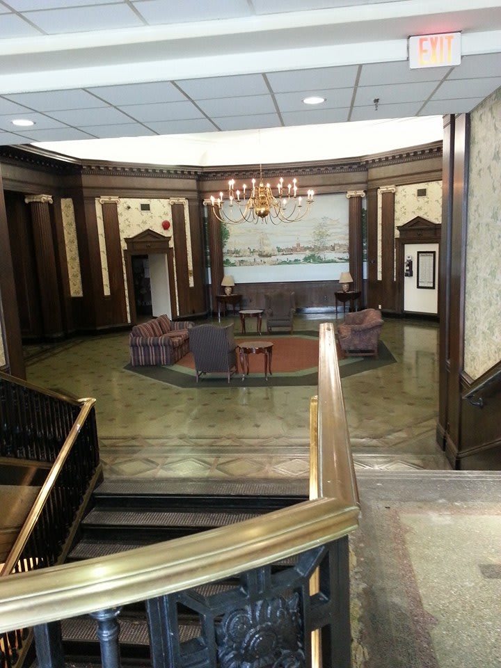 A stylish lobby featuring a central seating area, elegant wood paneling, and a chandelier.