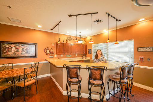 A modern kitchen with a bar area featuring stylish seating and warm orange walls.