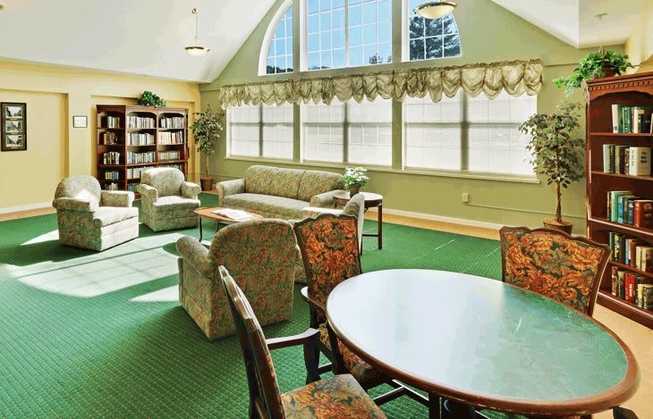 A cozy living room with large windows, comfortable seating, and bookshelves.