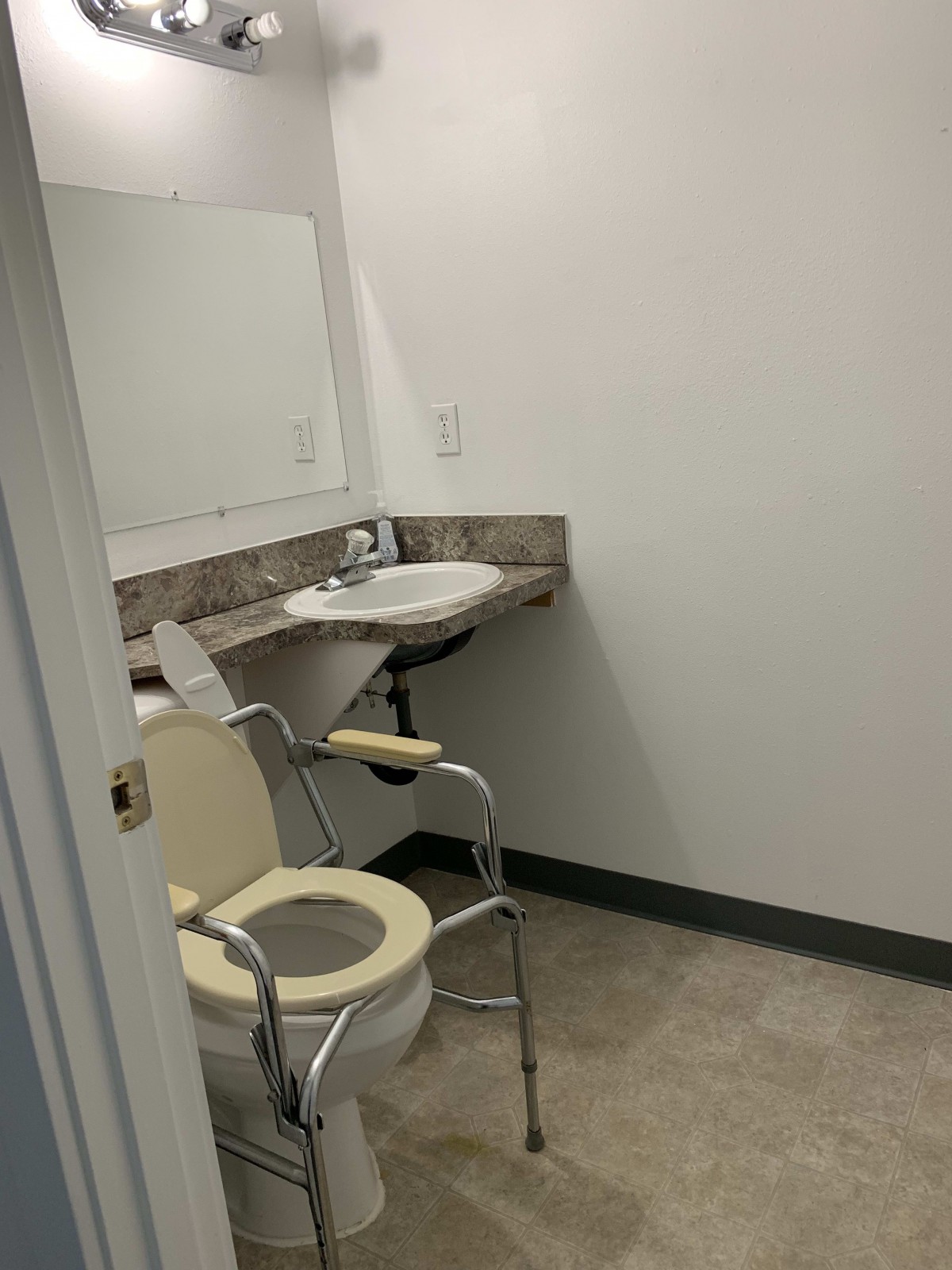 Accessible bathroom with a toilet chair and sink.