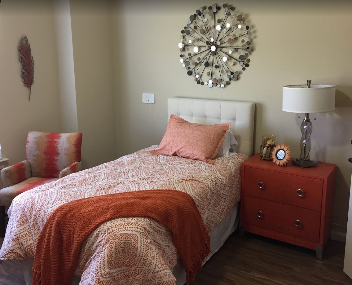 A cozy bedroom with a single bed, adorned with orange accents and stylish decor.