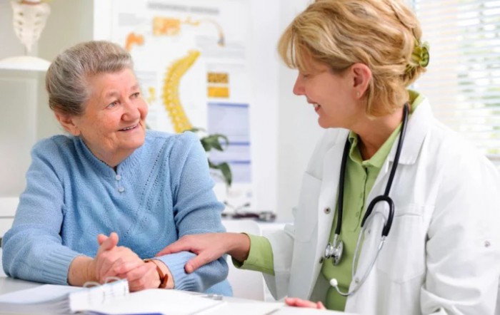 A doctor consulting with an elderly patient in a medical office.