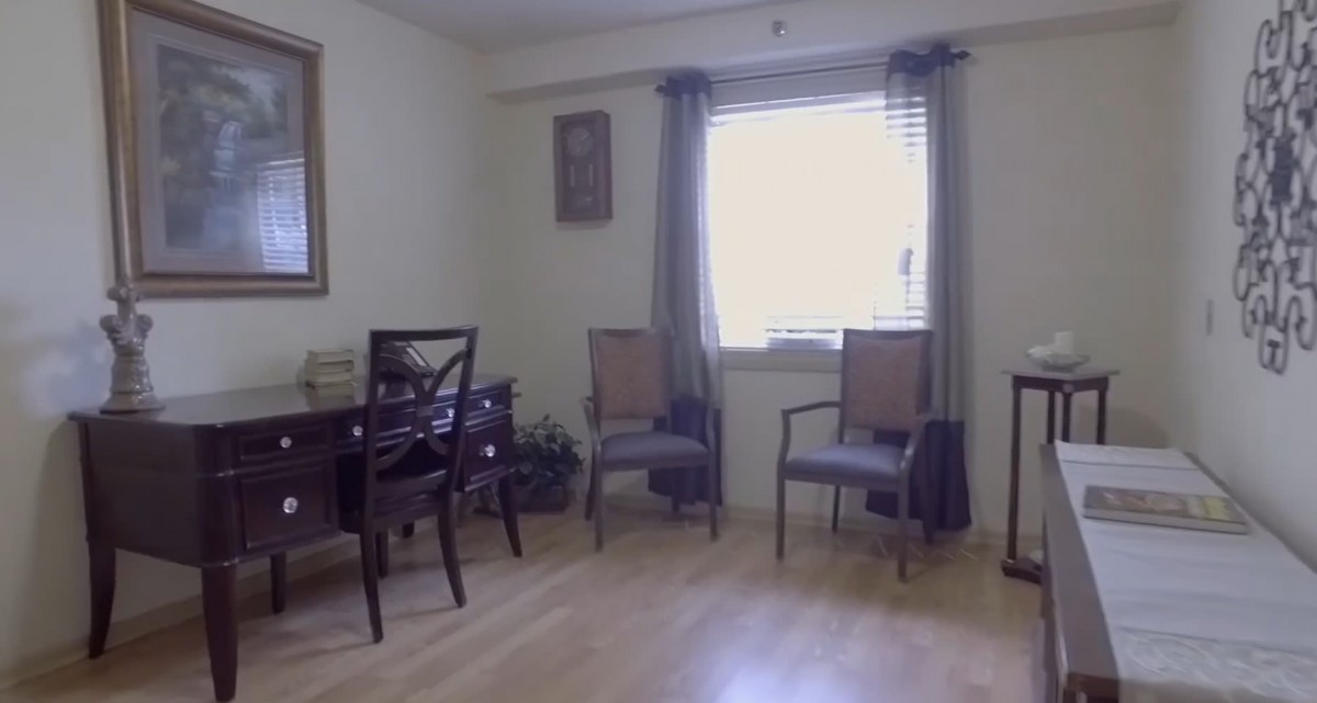 A neat and simple room with two chairs, a table, and a window with curtains.