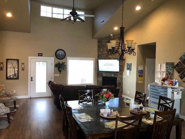 A cozy living room with high ceilings, featuring a dining table, sofa, television, and a decorative chandelier.