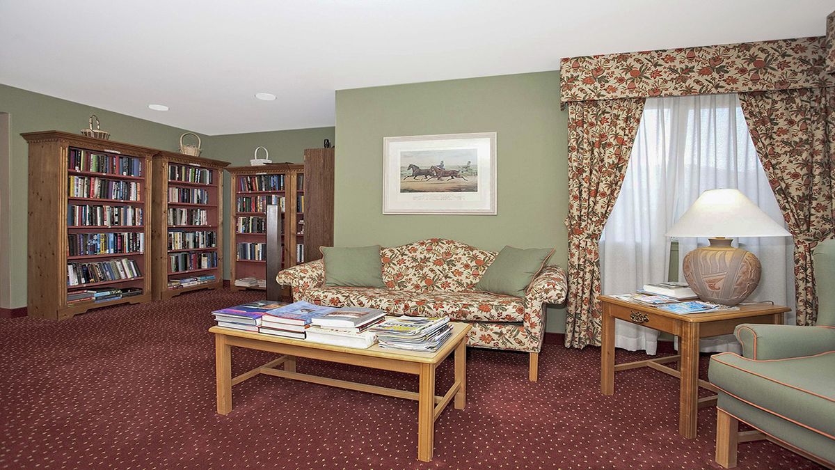 A cozy living room with a floral sofa, bookshelf, and coffee table.