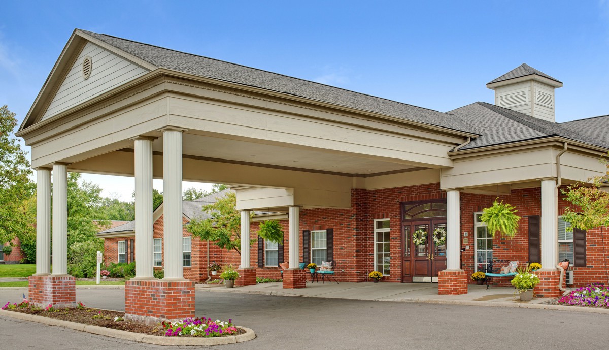 A brick building with a covered entrance supported by columns.