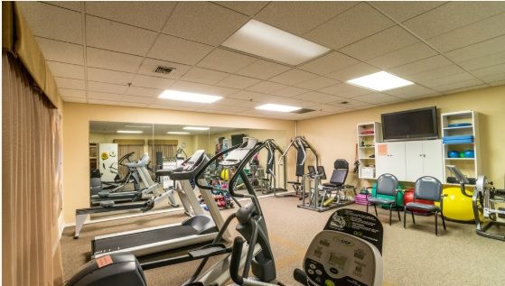 A well-equipped gym with various exercise machines including treadmills, an elliptical machine, and a stationary bike.