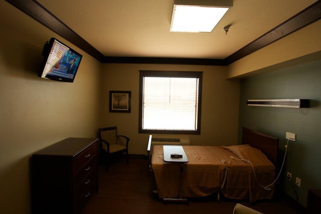 A hospital room with a bed, television, and window.