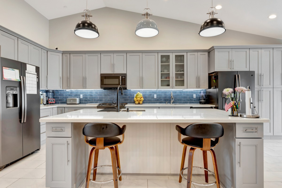 A modern kitchen with a central island, stylish bar stools, pendant lighting, and sleek cabinetry.