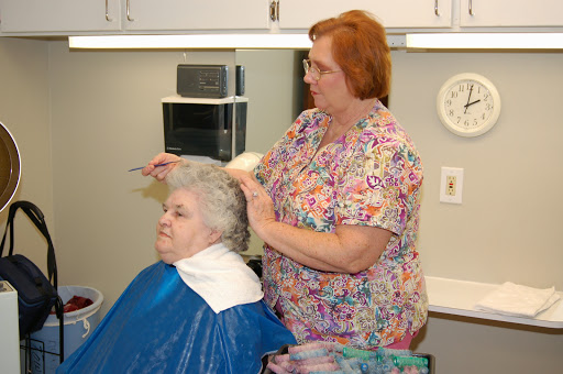 A hairdresser gives a haircut to a senior woman in a cozy salon setting.