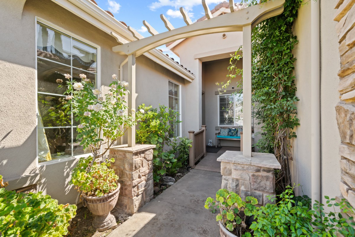A charming garden pathway with an arched pergola leading to a cozy patio area.