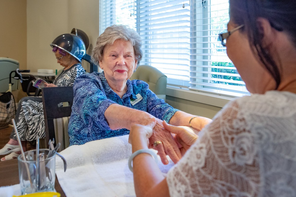 An elderly woman receiving a relaxing manicure at a spa salon.