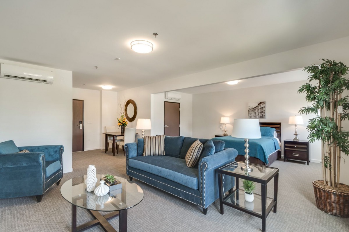 A modern living room interior with blue sofas, a glass coffee table, and stylish decor.